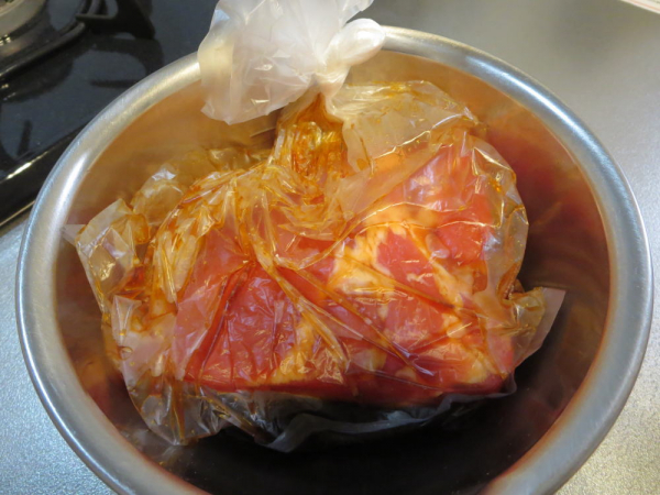ポリ袋に入れた豚バラ肉を調味料で漬け込む